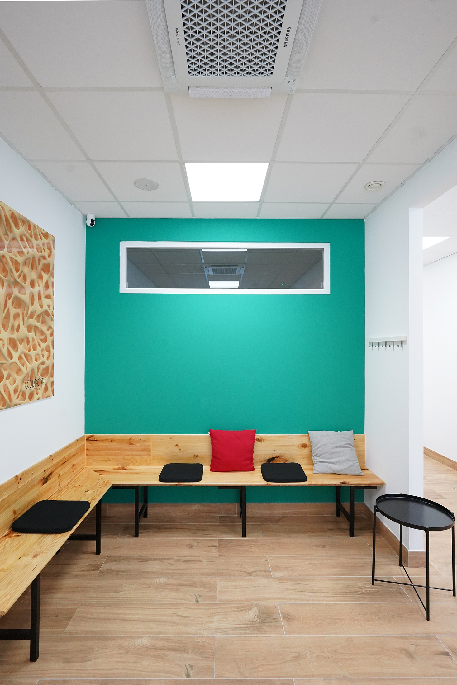 Detalle frontal del banco de madera a medida en la zona de espera con cojines